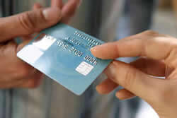 Stock photo of person handing credit card from one person to another