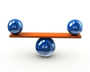 Stock photo of two blue balls balancing on a board above a centered blue ball