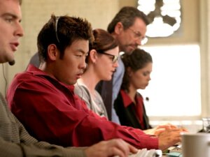 Stock photo of group of people training on keyboards, focusing on a screen (not pictured)