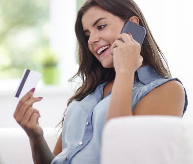 Woman staring at credit card on cell phone