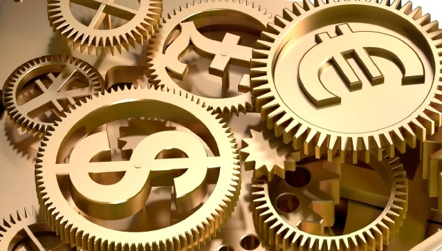 Stock photo of golden cogs with different international currency symbols